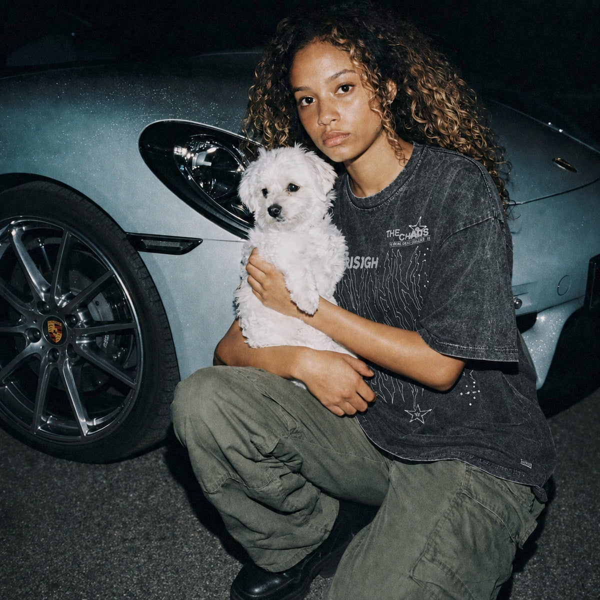 Femme portant le t-shirt RECKONING SEVN noir délavé avec un chien devant une voiture